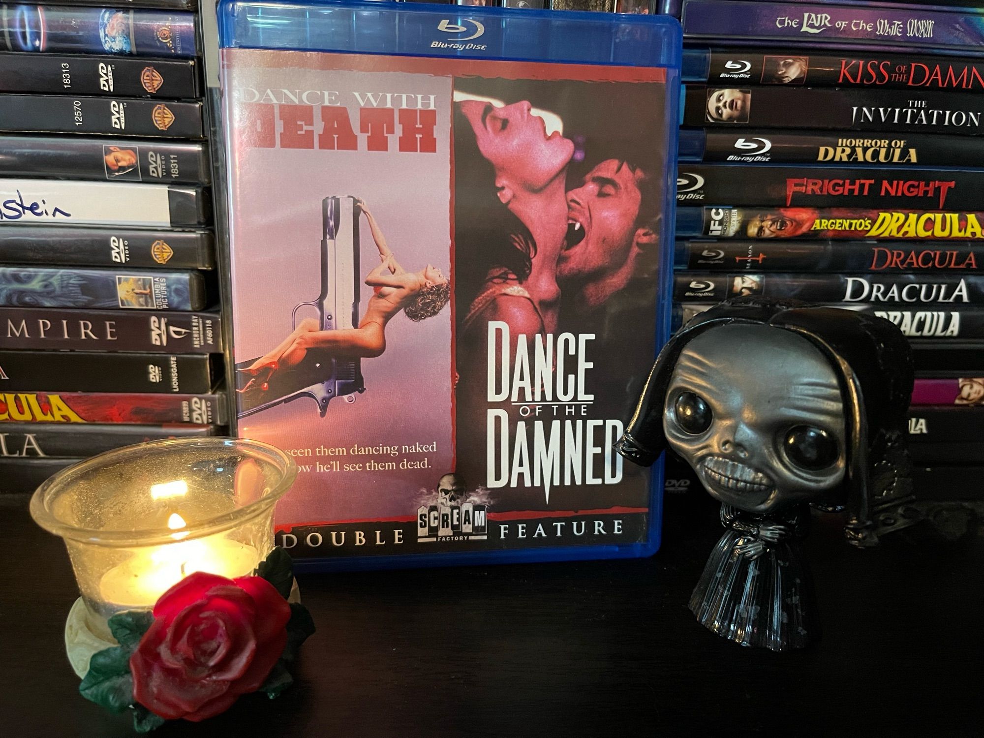Blu Ray of the movie Dance of the Damned on a DVD shelf sitting between Mother Ghost Funko Pop from Crimson Peak and a red rose tea light holder.
