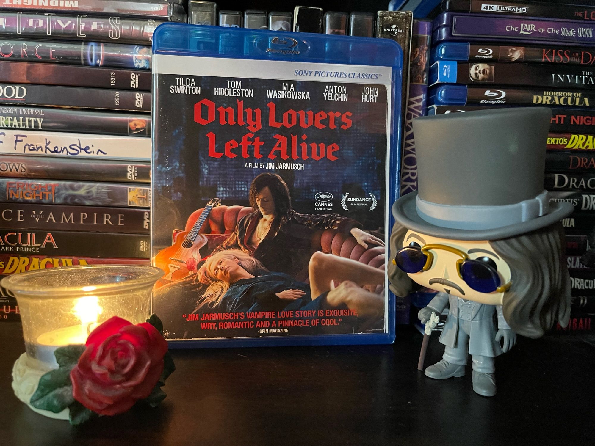 Blu ray copy of Only Lovers left alive on a DVD shelf of vampire movies, centered between a Dracula Funko Pop and a red rose tea light candle holder
